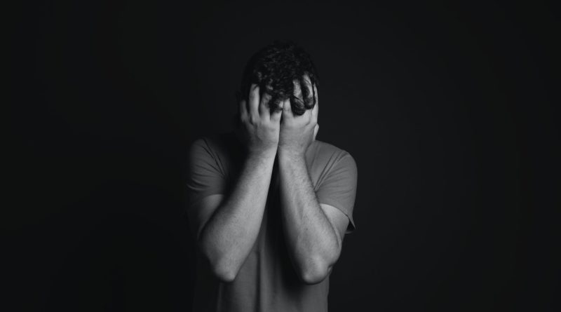 gray scale photo of man covering face with his hands