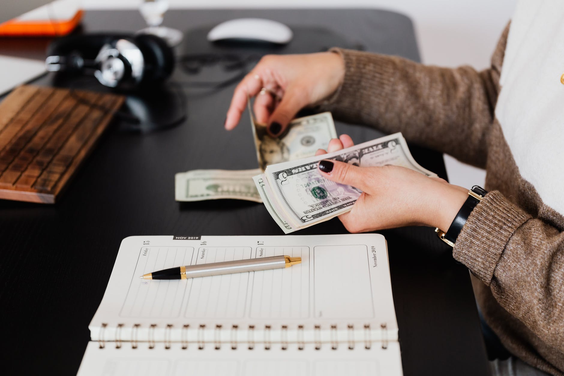 crop businesswoman counting money while sitting at desk