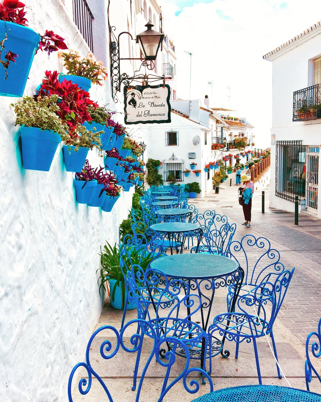 blue metal bistro sets near potted flowers and road