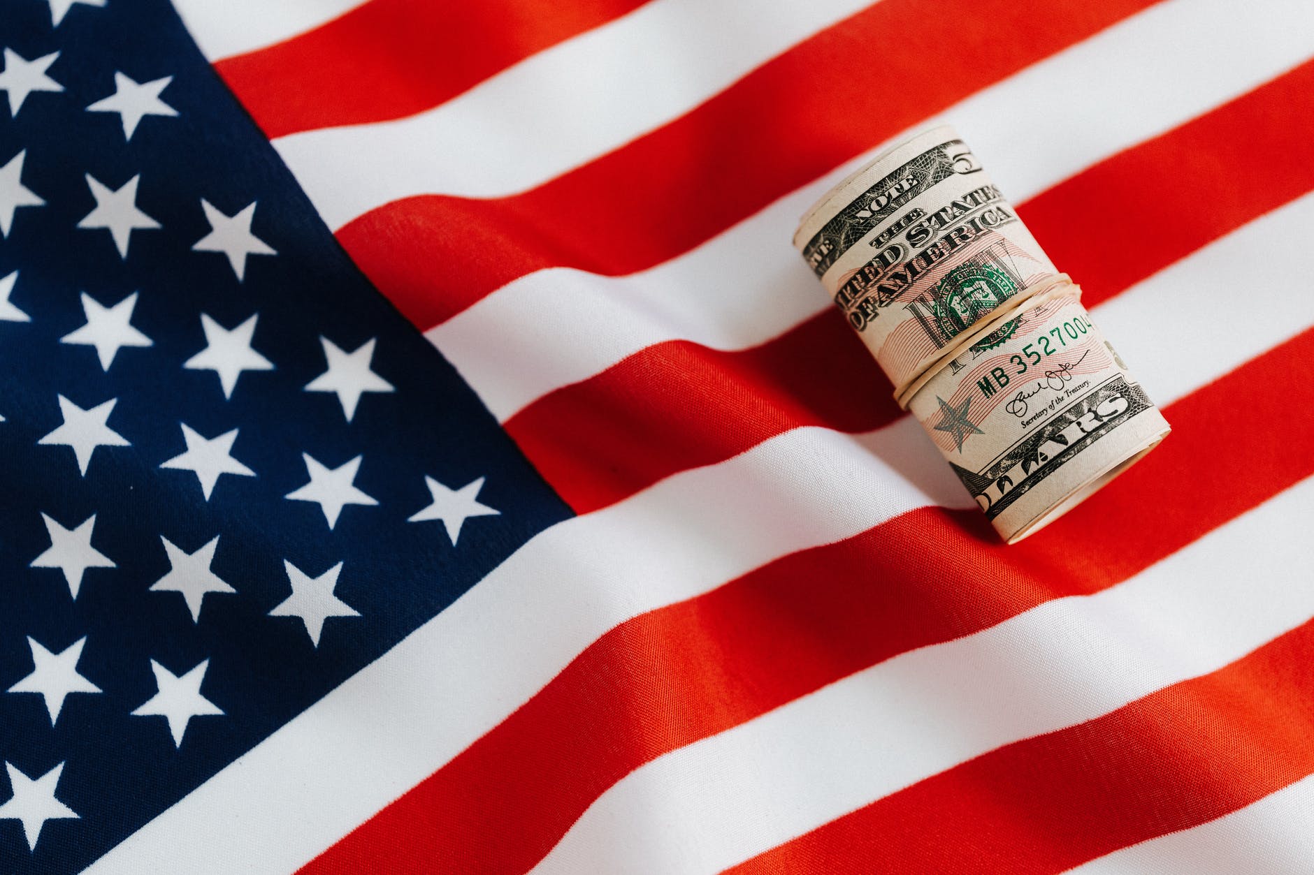 american flag with rolled dollar bills