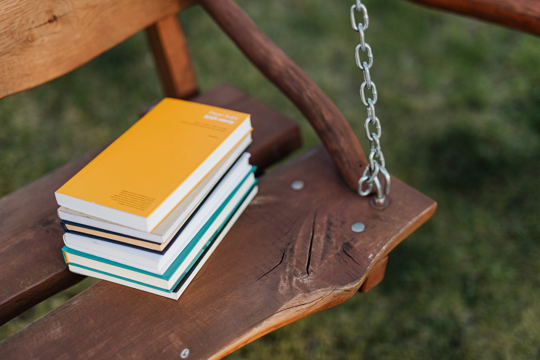 stack of books placed on seat of wooden swing