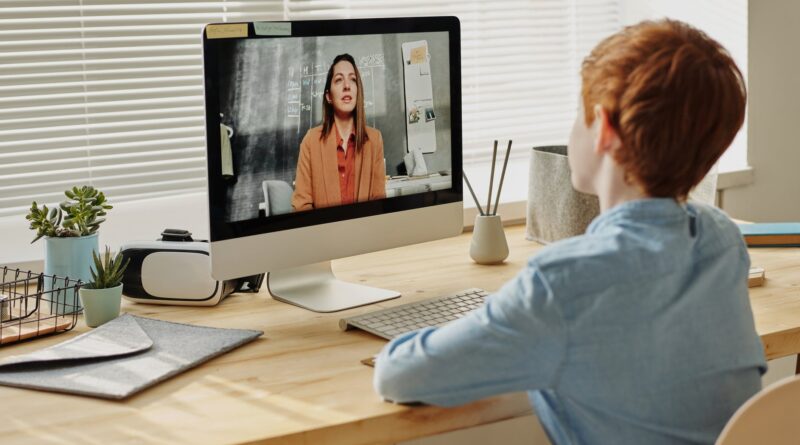 photo of child sitting by the table while looking at the imac