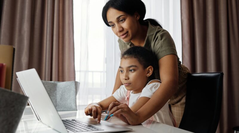 mother helping her daughter use a laptop