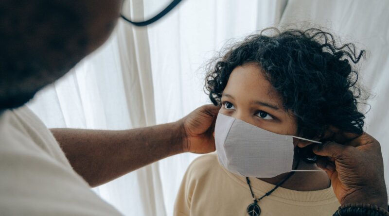 crop man putting medical mask on face of ethnic child