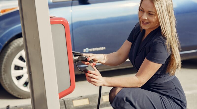 smiling woman using charging station for electromobile