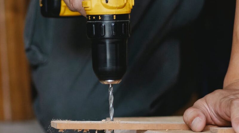 unrecognizable man drilling hole in wooden blank