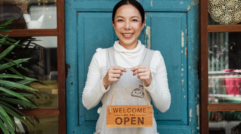 ethnic female cafe owner showing welcome we are open inscription