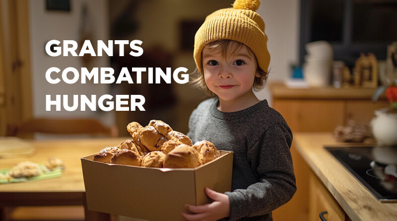 Small boy with curly blonde hair poking out from beneath his cap. He's holding a box of food.