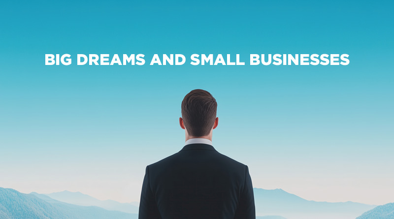 Businessman 's back, looking at a blue sky to signify looking to the future. He has Big Dreams and a Small Business.