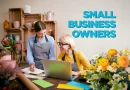 Business owner and employee sitting at a desk with flowers. The text reads Small Business Grants