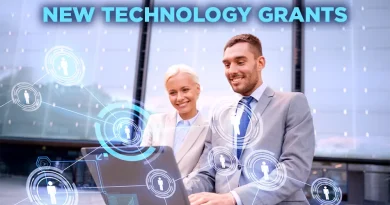 Two business professionals sitting outside and smiling while working on a laptop, with digital network graphics overlaying the image and the words 'New Technology Grants' displayed above them.