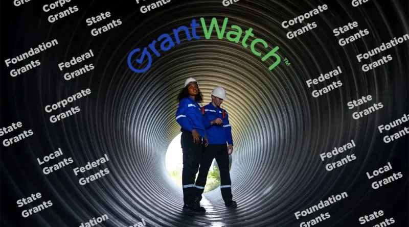Two workers wearing safety helmets and blue uniforms stand inside a large industrial pipe. The word “GrantWatch” appears above them, surrounded by repeated text labels such as “Federal Grants,” “State Grants,” “Local Grants,” “Corporate Grants,” and “Foundation Grants,” representing different types of funding sources.