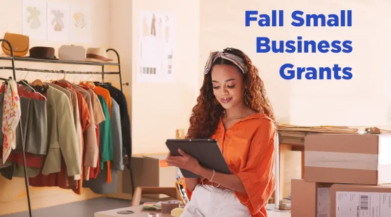 Young woman entrepreneur checking inventory in her clothing store with the text overlay 'Fall Small Business Grants'