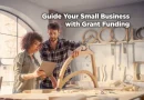 A woman and a man work together in a woodworking studio, reviewing plans on a tablet while examining a wooden frame. Text on the image reads, “Guide Your Small Business with Grant Funding.”