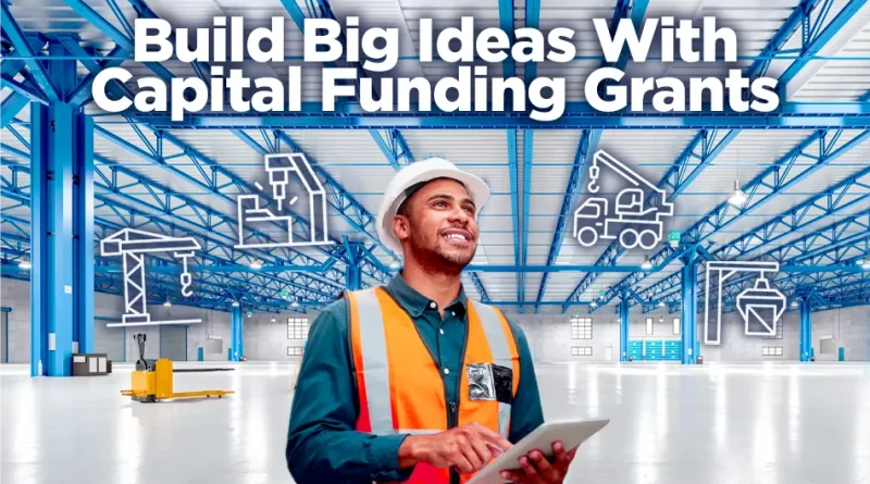 A construction project manager wearing a hard hat and safety vest smiles while holding a tablet inside a large, bright industrial warehouse. Blue steel beams span the ceiling, and white line-art icons of construction equipment—cranes, drills, and trucks—float around him. Bold text reads: 'Build Big Ideas With Capital Funding Grants.'