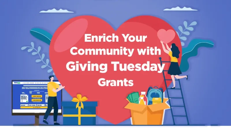 Illustration of two people placing hearts and gifts in front of a large red heart with the text “Enrich Your Community with Giving Tuesday Grants.” One person stands on a ladder holding a heart, while another stands near a computer displaying the GrantWatch website. A gift box and donation items sit at the center. The GrantWatch logo is at the bottom right.