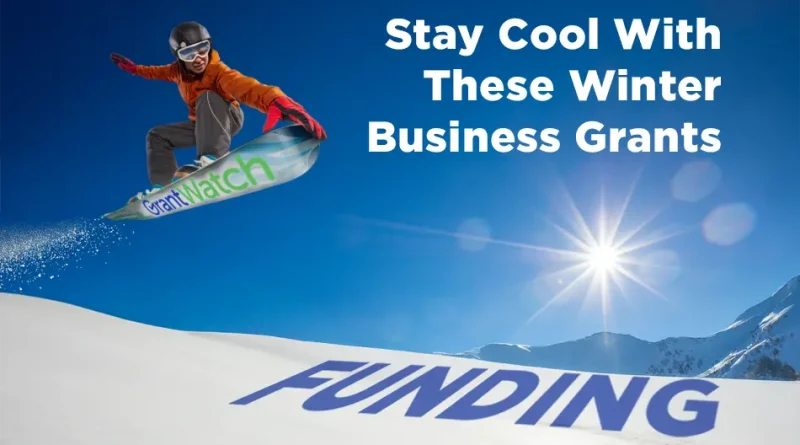 A snowboarder jumps across a snowy mountain slope on a snowboard labeled “GrantWatch,” with the word “FUNDING” printed in large letters on the snow and the text “Stay Cool With These Winter Business Grants” in the sky above.
