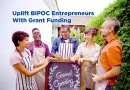 A diverse group of people standing in front of a restaurant for the grand opening of their business. Words above their heads reads "Uplift BIPOC Entrepreneurs with Grant Funding."