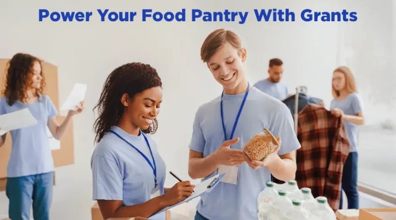 Volunteers in blue shirts organize food donations at a pantry, with one person checking inventory on a clipboard while another holds a jar of beans. Boxes of supplies and bottled drinks sit on a table, and a banner above reads, “Power Your Food Pantry With Grants.”