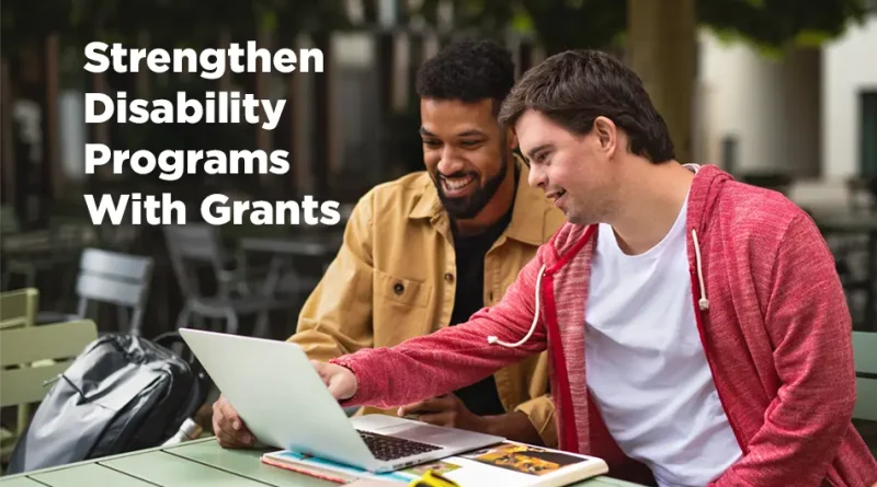 Two men sit looking at a laptop. One is disabled and the other is guiding him. Both are smiling and happy. The text reads " Strengthen disability programs With Grants."