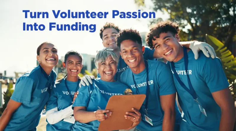 A diverse group of smiling volunteers wearing blue shirts stand closely together outdoors, some with lanyards and one holding a clipboard, suggesting teamwork and community service. Sunlight filters through trees in the background. Text on the image reads: “Turn Volunteer Passion Into Funding.”