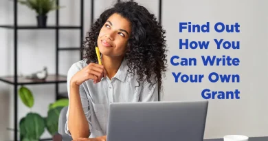 A woman, sitting in front of her laptop, looking whimsically up to her right, lost in thought. She ponders the caption: " Find Out How You Can Write Your Own Grant."