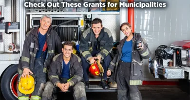 A group of firefighters pose for a group photo. They represent the good that municipalities can achieve. The caption reads: "Check Out These Grants for Municipalities."
