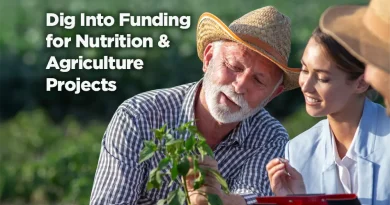 Generational teaching moment caught in this image. A white-haired man teaches youngsters about the plant he holds in his hands. They are outside and the lesson is going well. Caption reads: Dig into Funding for Nutrition and Agriculture Projects.