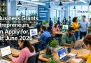 6 Small Business Grants Entrepreneurs Can Apply for This June A busy modern office filled with entrepreneurs and professionals working at desks, collaborating in small groups, and using laptops in a bright, open workspace with plants throughout. Large text on the left reads, “6 Business Grants Entrepreneurs Can Apply for This June 2026.” A GrantWatch logo appears in the upper right corner. The office atmosphere conveys innovation, teamwork, and business growth, with a wall sign in the background displaying the words “Focus, Collaborate, Innovate, Succeed.”