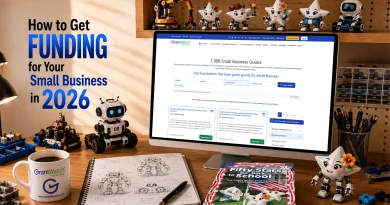 Desktop workspace with a computer displaying GrantWatch small business grants, surrounded by educational robots, robotics blueprints, and a book. Large text reads, “How to Get Funding for Your Small Business in 2026.” GrantWatch-branded coffee mug on desk.