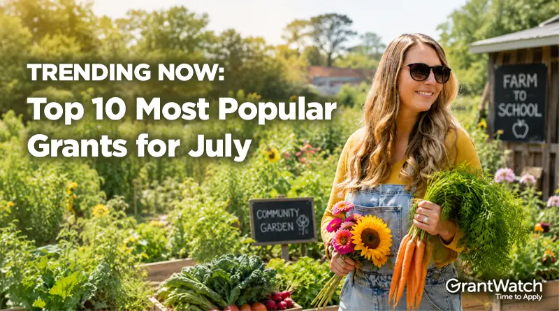 A woman wearing sunglasses stands in a thriving community garden holding freshly harvested carrots and a bouquet of flowers. Garden beds filled with vegetables and greenery surround her, while signs reading "Community Garden" and "Farm to School" appear in the background. Overlay text reads: "TRENDING NOW: Top 10 Most Popular Grants for July." The GrantWatch logo appears in the bottom-right corner.