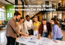 A diverse group of entrepreneurs and startup professionals gather around a table in a modern coworking space, reviewing business plans and funding strategies. Text overlay reads: "Grants for Startups: Where Entrepreneurs Can Find Funding."
