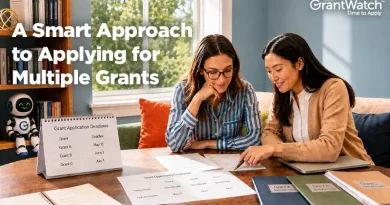Two women sit at a table reviewing grant application materials and deadlines while planning multiple funding submissions. Documents, folders, and a calendar displaying grant deadlines are spread across the table. A bookshelf and window create a professional office setting. On-screen text reads, “A Smart Approach to Applying for Multiple Grants,” with the GrantWatch logo in the upper-right corner.